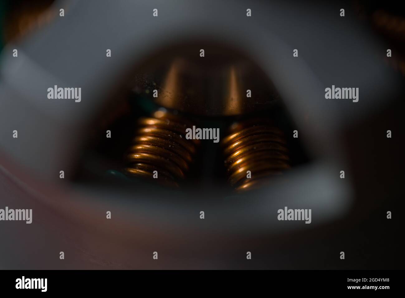 Dunkle Nahaufnahme von glänzenden Kupferspulen innerhalb eines bürstenlosen Drohnenmotors. Kopierbereich und selektiver Fokus mit filmischen Farben. Super-Makro-Skala. Stockfoto