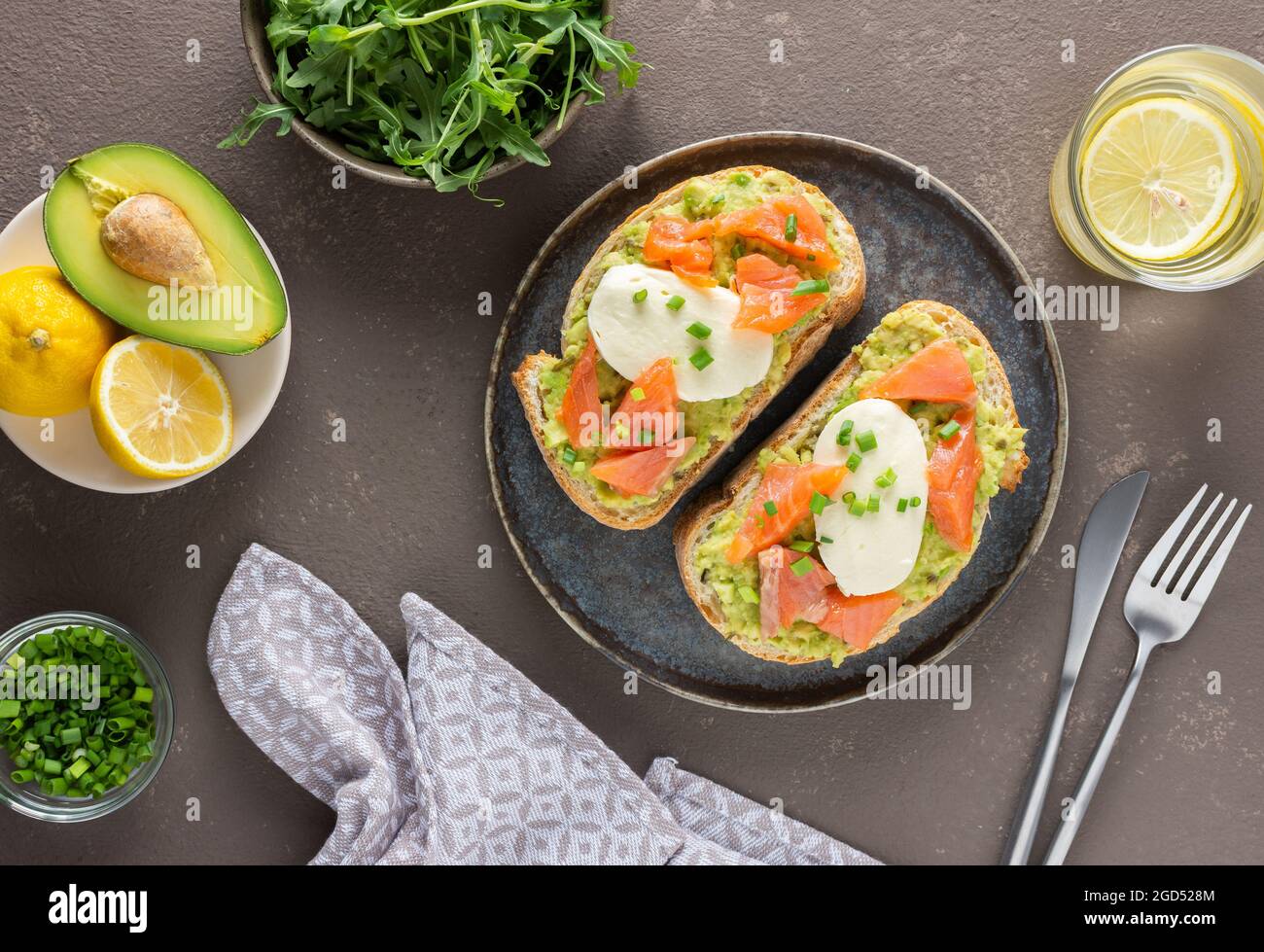 Leckeres herzhaftes Frühstück, Sandwiches mit Avocado-Paste, Lachs und Mozzarella auf einem Teller, Rucola und Erbsensprossen und grüne Zwiebel Stockfoto
