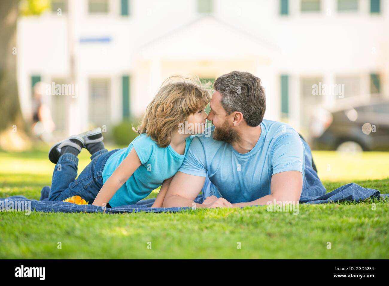 Glücklicher Vater mit Sohn entspannen zusammen auf grünem Parkgras, Vaterschaft Stockfoto