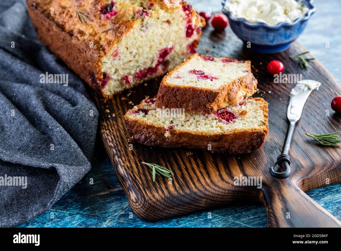 Nahaufnahme eines Preiselbeer-Rosmarinbrotes mit Scheiben vorne und Frischkäse hinten. Stockfoto