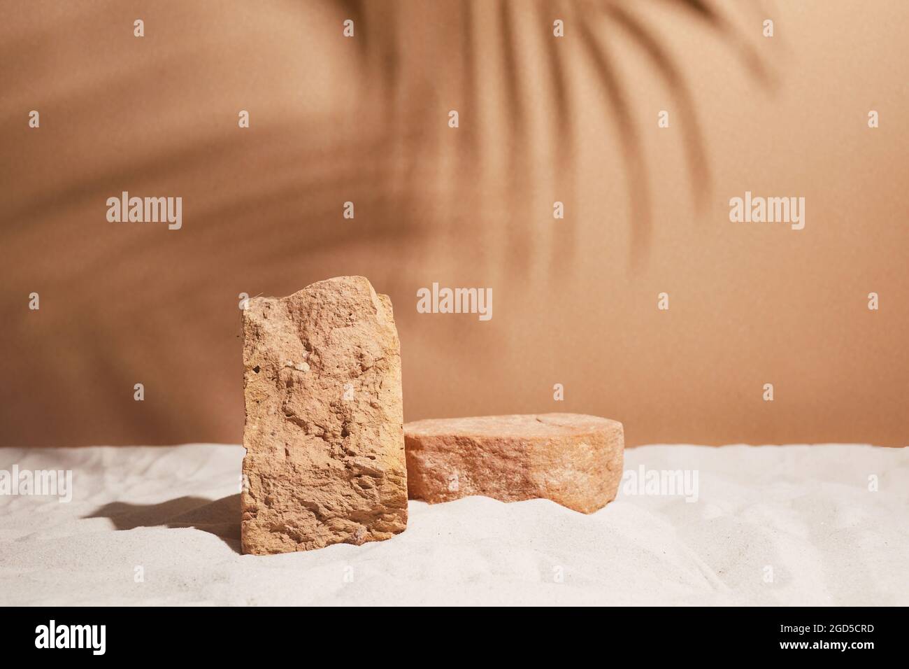 Podium auf Sandhintergrund. Display mit Sonnenschirm und Schatten auf dem Hintergrund für kosmetische Parfüm Mode Naturprodukt Stockfoto