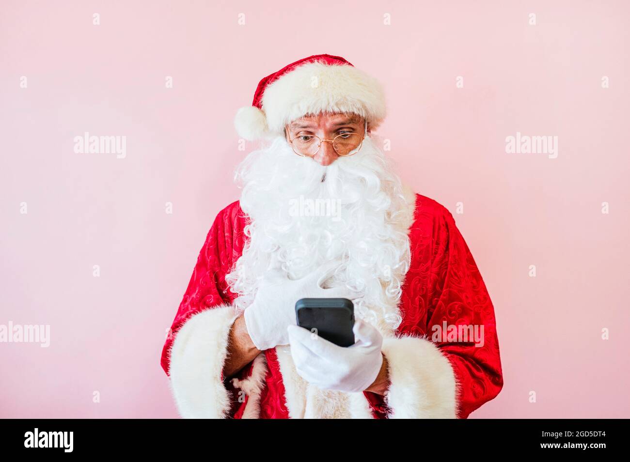 Mann als Weihnachtsmann mit Smartphone gekleidet Stockfoto