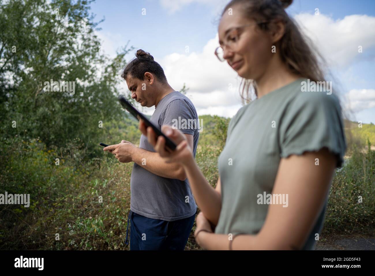 Junge Männer und Frauen, die auf die Bildschirme ihrer Smartphones schauen Stockfoto