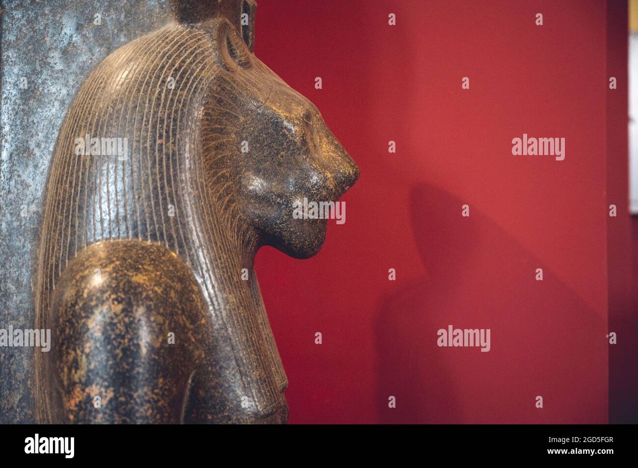 Nahaufnahme einer ägyptischen Pharao-Statue aus Stein neben der roten Mauer Stockfoto