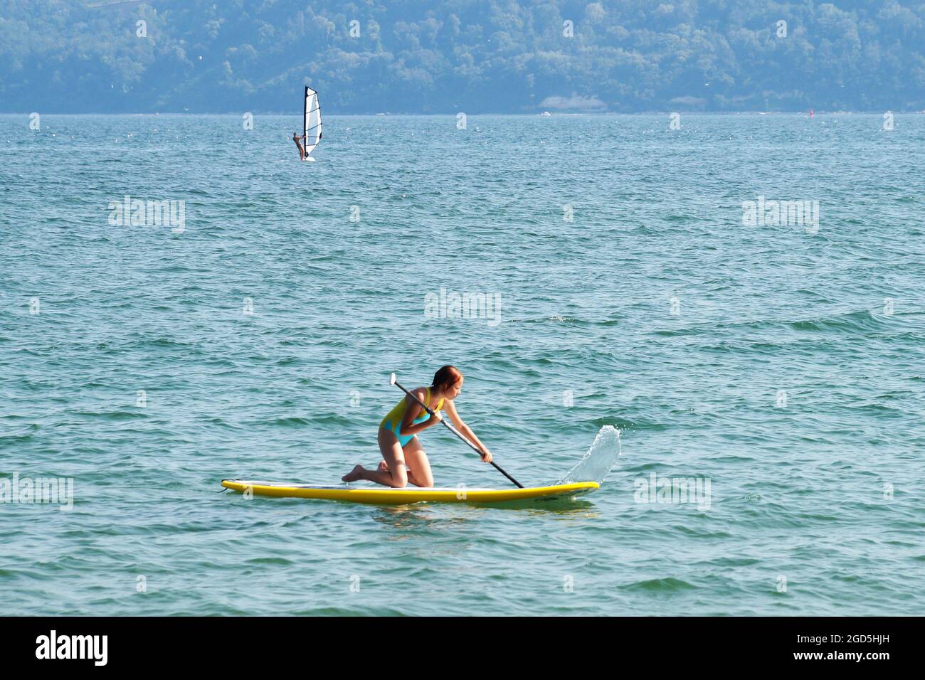 Teenager-Mädchen, das auf den Knien im Meer auf dem Rücken reitet. Stockfoto