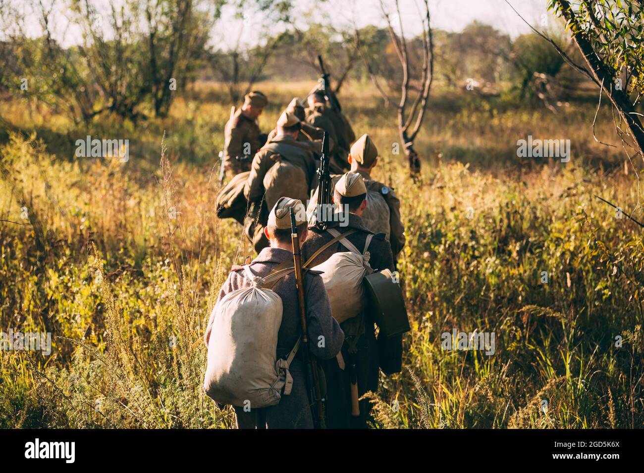 Eine Gruppe von nicht identifizierten Re-enactors, die als russische Soldaten gekleidet sind, geht auf der Wiese entlang Stockfoto