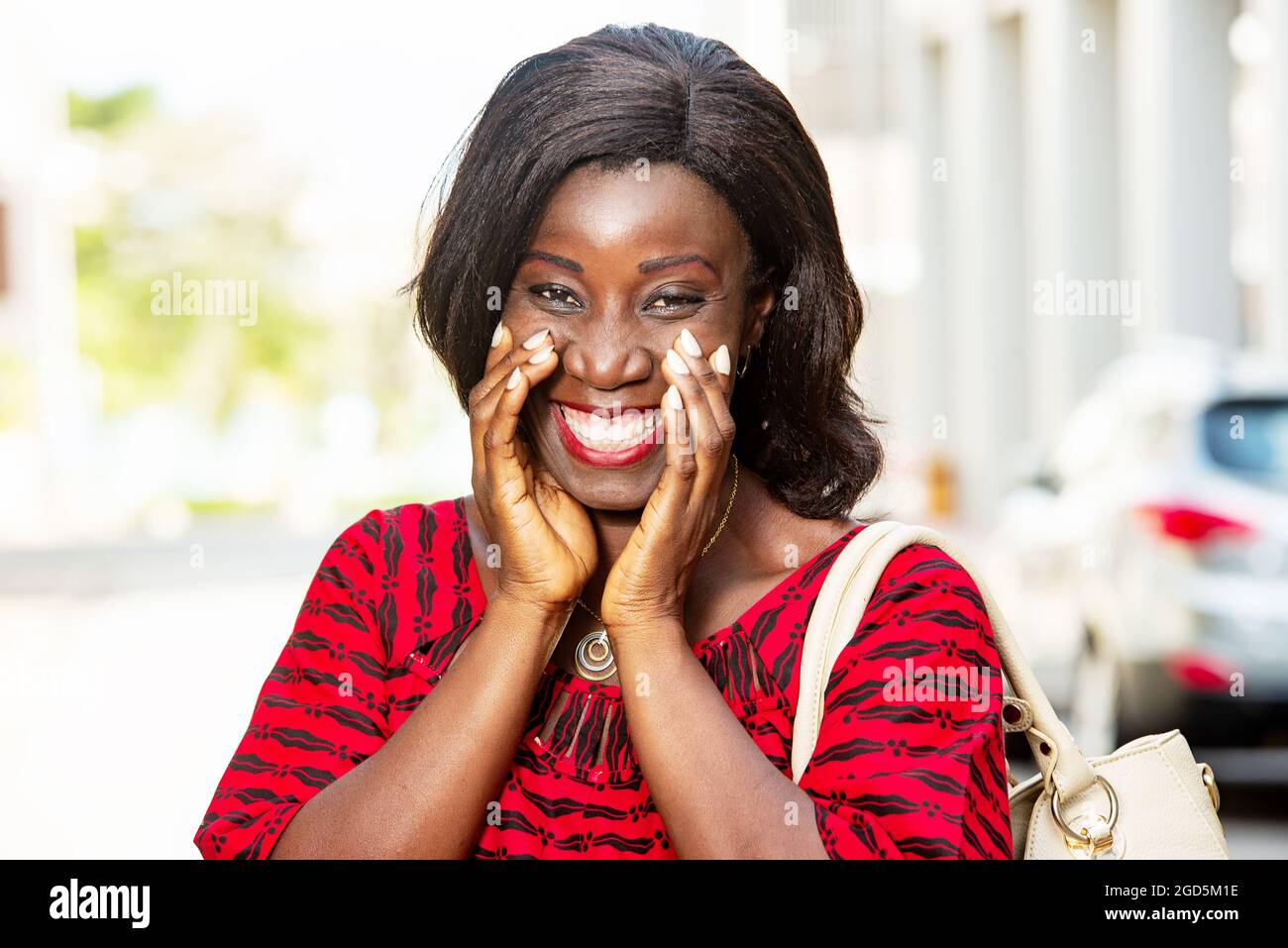 Reife afrikanische Frau im Freien stehend Blick auf Kamera lächelnd mit Handtasche. Stockfoto