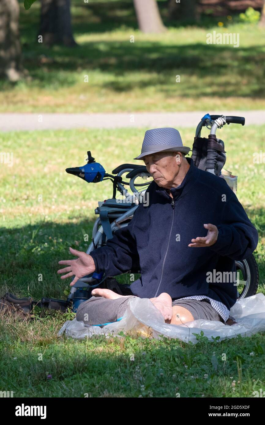 Ein 86-jähriger Chinese, ein amerikanischer Mann, praktiziert in der Nähe eines Baumes in einem Park in Flushing, Queens, New York City, die langsamen Falun Gong-Übungen. Stockfoto