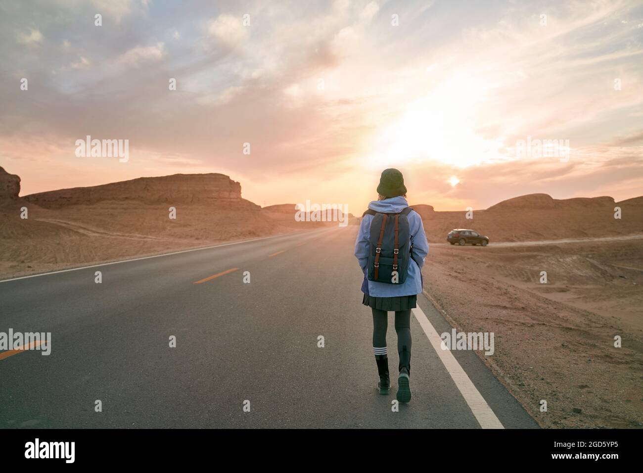 Rückansicht einer Reisenden Frau, die auf der Autobahn in der wüste gobi mit ihren Yardang-Landformen unterwegs ist Stockfoto