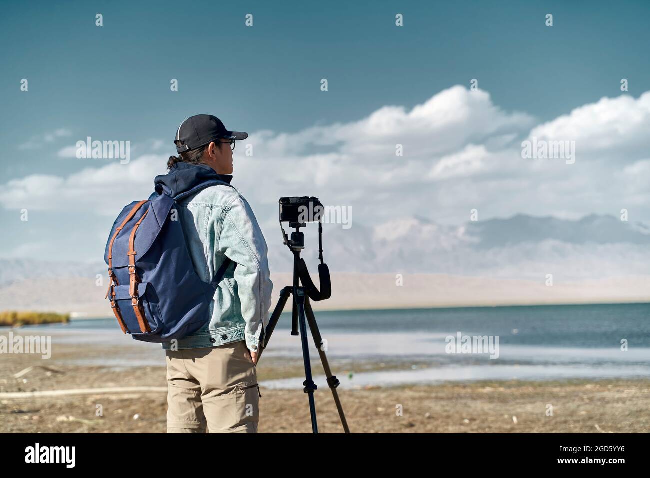 asiatischer Fotograf, der an einem See steht und die Aussicht beobachtet Stockfoto