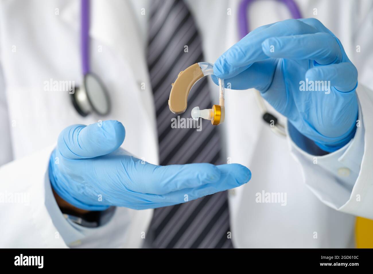 Otorhinolaryngologe, der Hörgeräte mit Gummihandschuhen in der Nähe hält Stockfoto