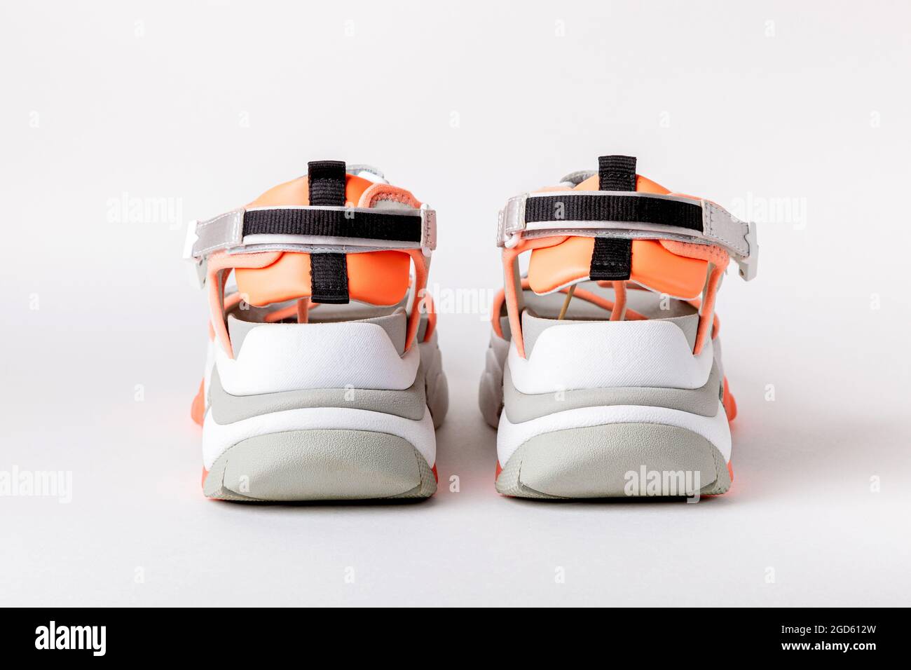 Modische Damen-Sportsandalen mit orangefarbenen Akzenten auf weißem Hintergrund. Neue Jugendschuhe für Mädchen. Stockfoto