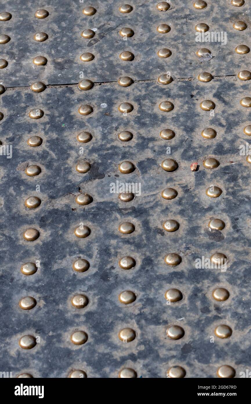 Taktile Pflasterung, Behindertenhilfe, Blindheit, Messingbolzen in Beton, Ansatz zur Fußkreuzung, Hilfe bei der Kreuzung von Straßen, Muster, abstrakt Stockfoto