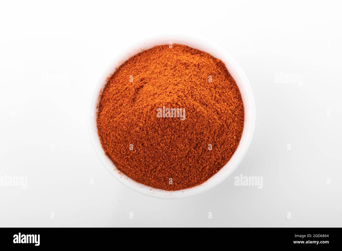 Rotes Paprikapulver. Pfefferpulver in weißer Schüssel, auf weißem Hintergrund. Makro Schuss peppepulver. Stockfoto