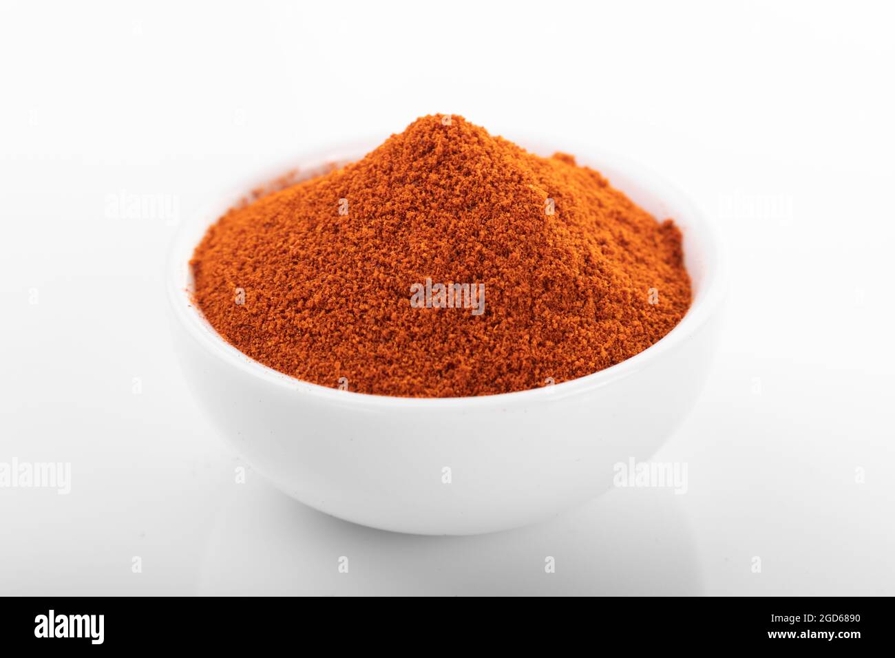 Rotes Paprikapulver. Pfefferpulver in weißer Schüssel, auf weißem Hintergrund. Makro Schuss peppepulver. Stockfoto