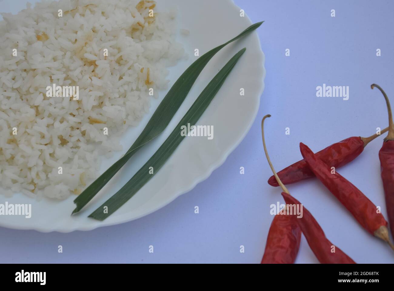 Nahaufnahme von Reis auf weißem Teller mit roten Chilischoten auf weißem Hintergrund isoliert Stockfoto