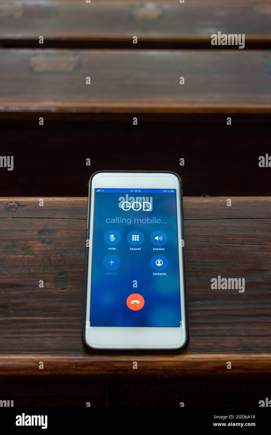 Gott rufen mit einem Handy auf dem Tisch einer Gebetsbank in der Kirche, aus der Nähe. Stockfoto