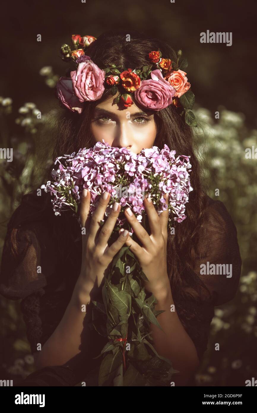 Schönheitsporträt der jungen Frau mit Blumen im Feld Stockfoto