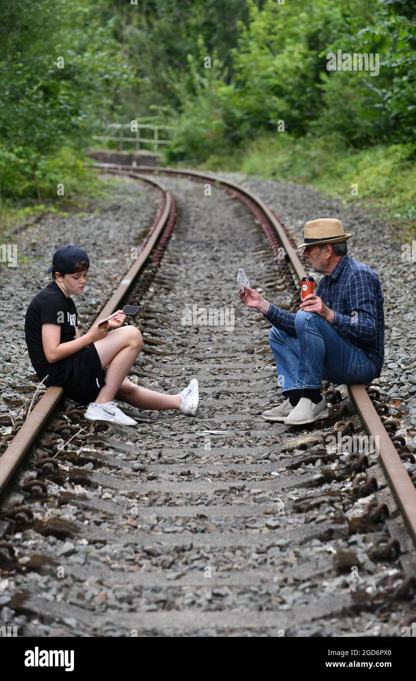 Mann und Junge spielen Karten auf der Eisenbahnstrecke Großbritannien, Großbritannien spielen Glücksspiel Stockfoto