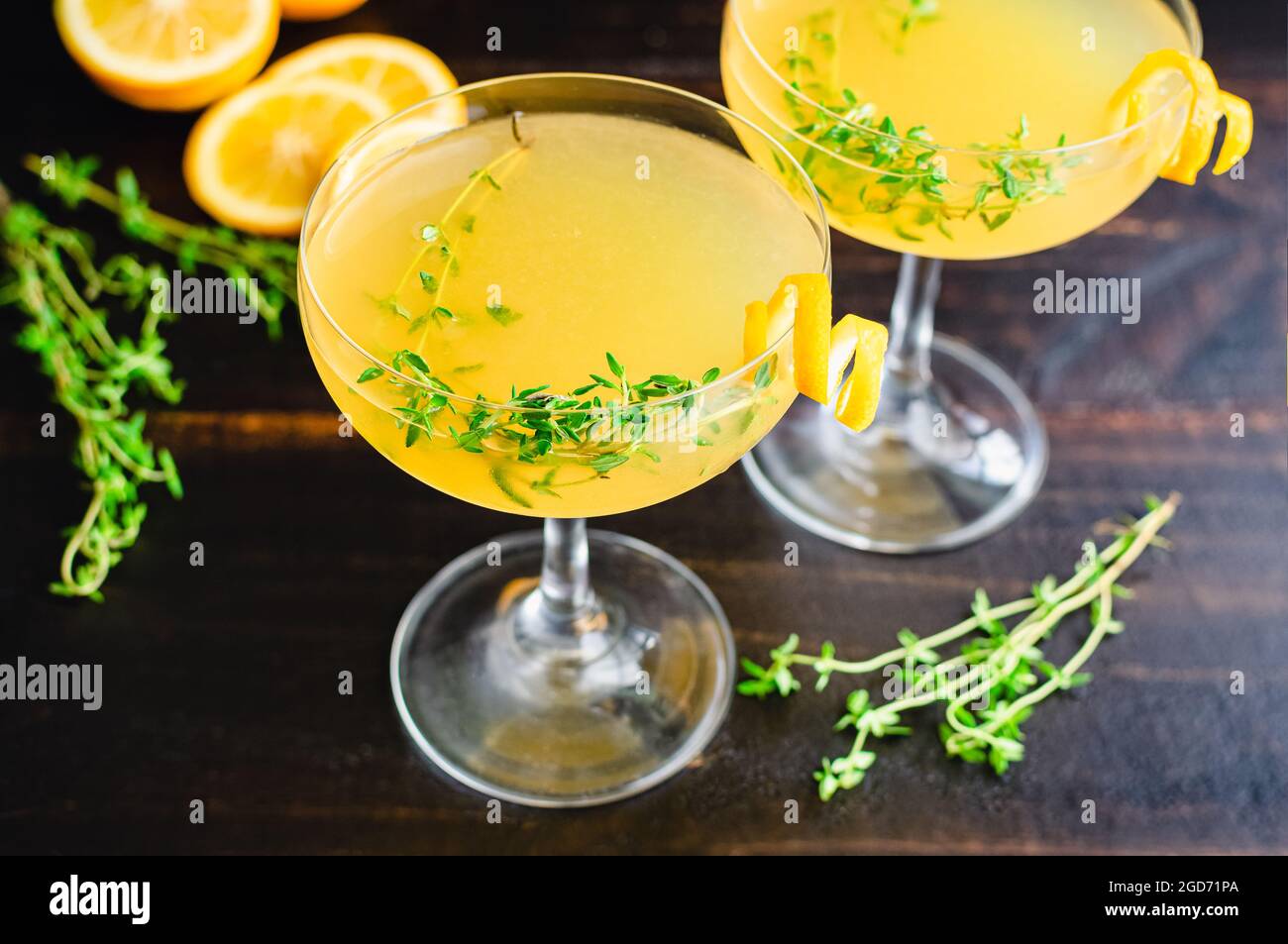 Meyer Lemon and Thyme Bees Knees Cocktails: Gin-Cocktails mit Meyer Zitronensaft und garniert mit Thymiansprigs und einem Twist Stockfoto