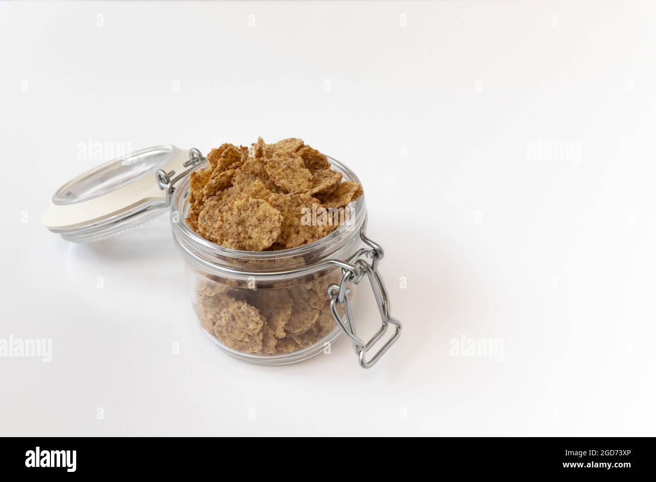 Getreideflocken im Glas isoliert auf weißem Hintergrund, Lebensmittelzutat, gesundes Frühstück Stockfoto