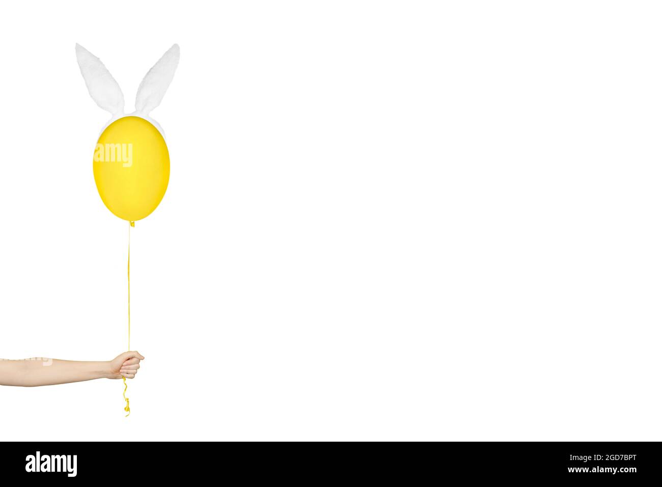 Kreatives osterkonzept mit minimalem Aufwand. Hand hält einen gelben Ballon in Hasenohren isoliert auf weiß. Monochromes Banner mit Kopierbereich. Stockfoto