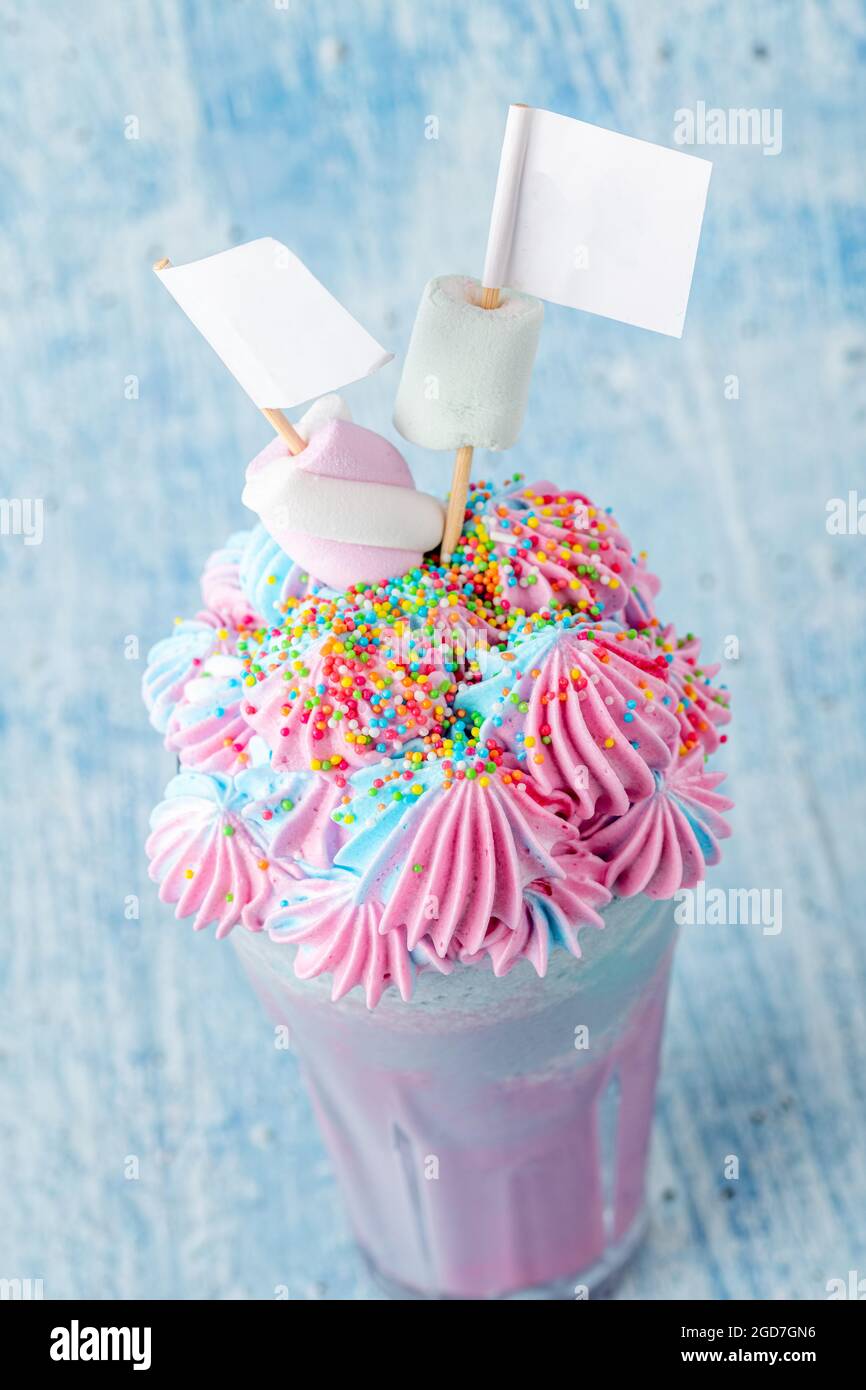 Blauer und rosafarbener Milchshake mit Marshallows auf blauem Hintergrund. Stockfoto
