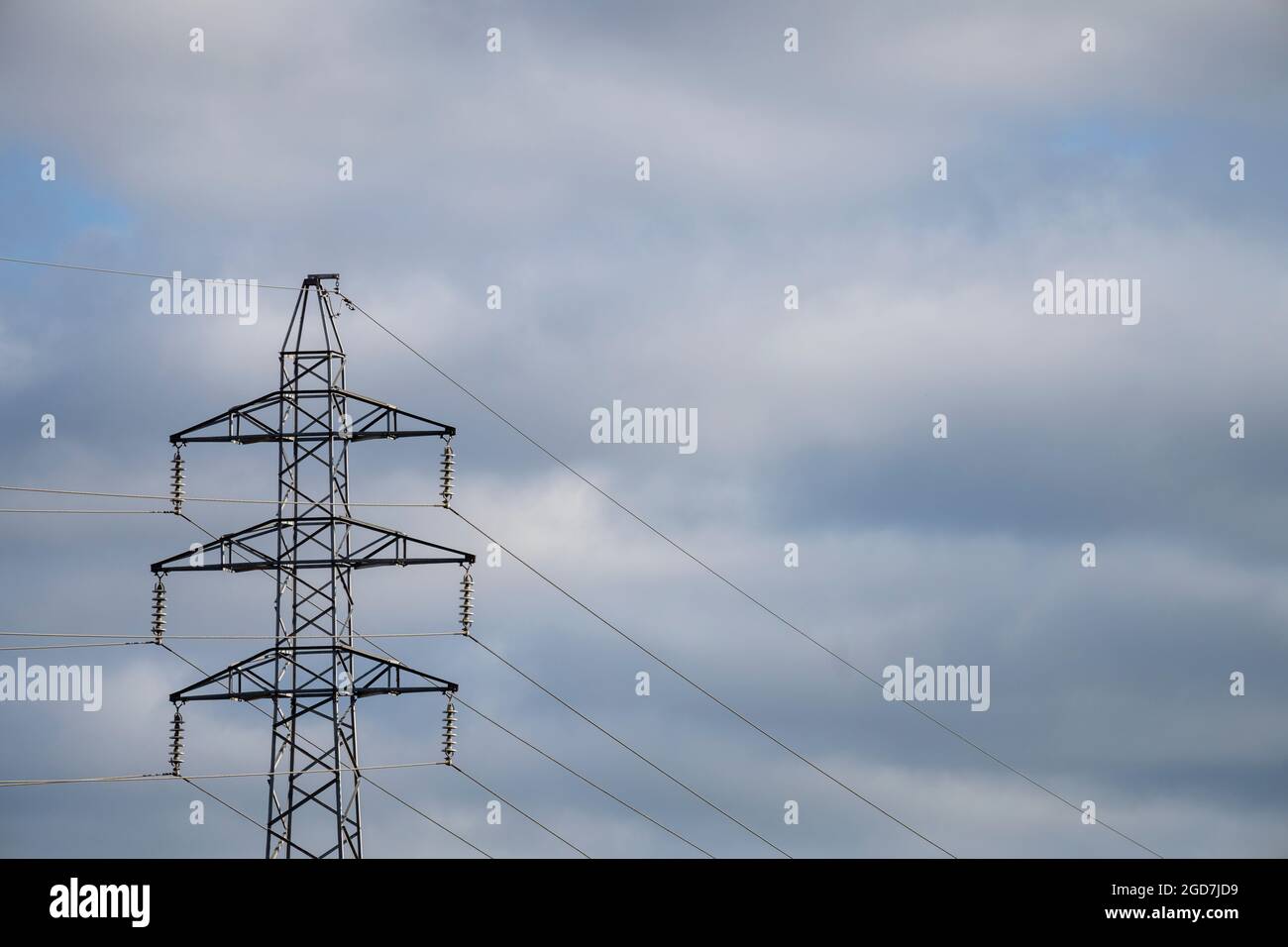 Elektrischer Mast am wolkigen blauen Himmel Stockfoto