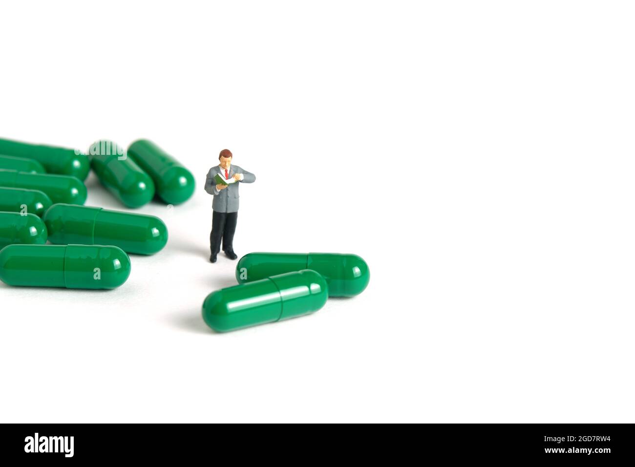 Miniatur Menschen Spielzeug Figur Fotografie. Ein männler Student, der mitten in der Medikamentenpille steht und die Zutat liest. Bildfoto Stockfoto