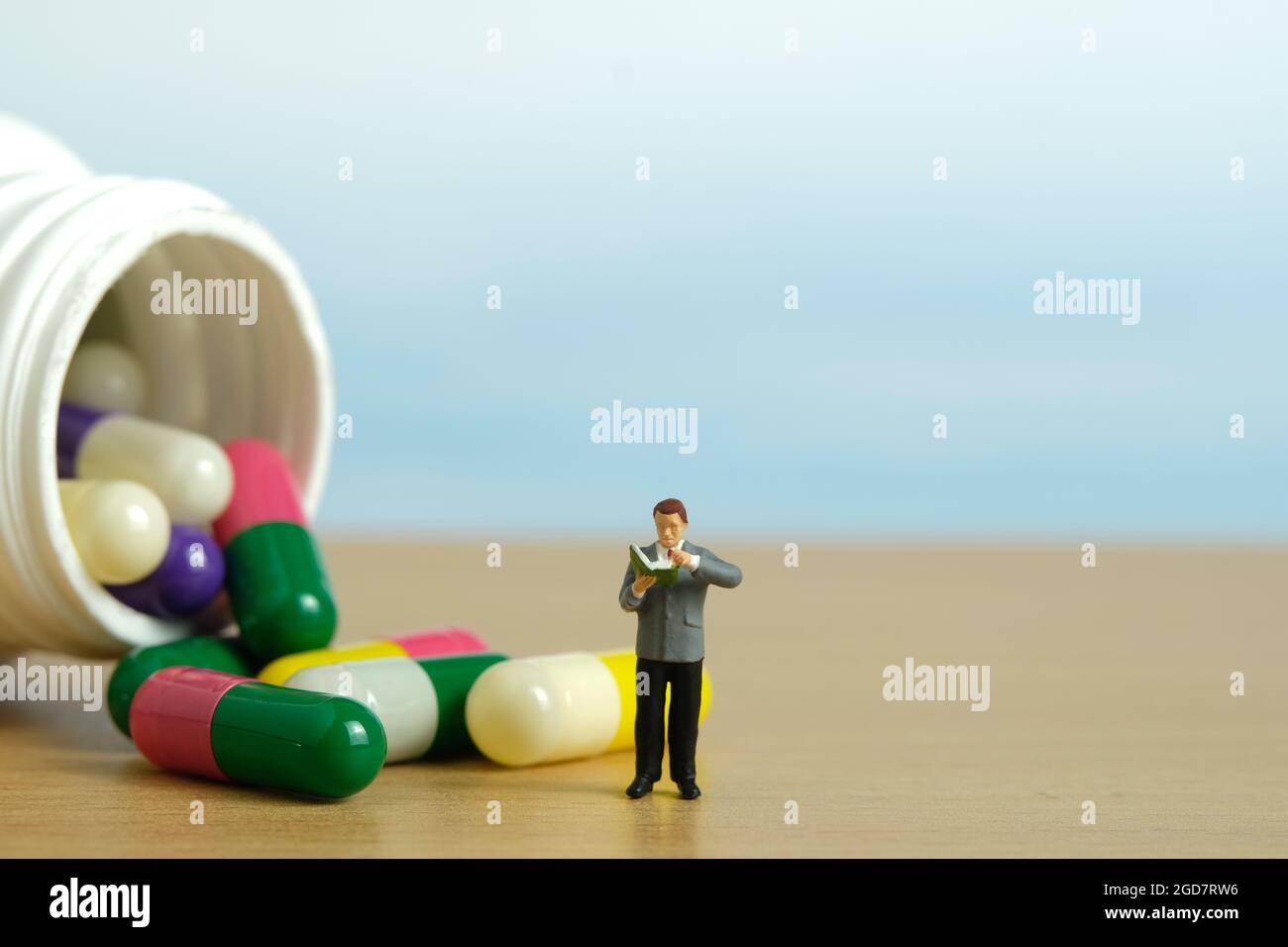 Miniatur Menschen Spielzeug Figur Fotografie. Ein männler Student, der mitten in der Medikamentenpille steht und die Zutat liest. Bildfoto Stockfoto