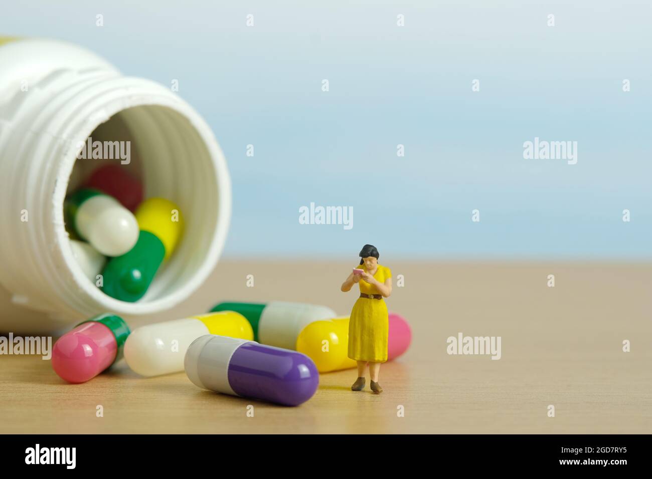 Miniatur Menschen Spielzeug Figur Fotografie. Eine Studentin, die mitten in der Medikamentenpille steht und die Zutat liest. Bildfoto Stockfoto