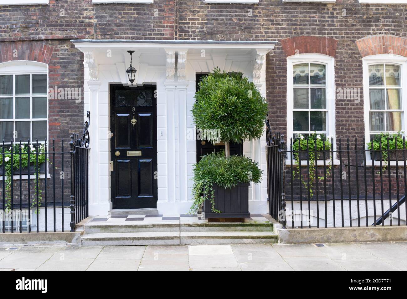 Zwei Vordertüren nebeneinander mit großem Baumbepflanzer auf der rechten Seite Nachbarn London England Stockfoto