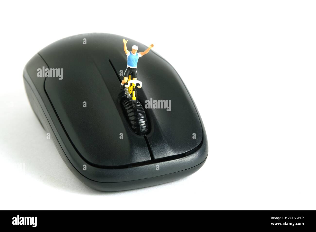 Miniatur Menschen Spielzeug Figur Fotografie. Kreatives Konzept. Ein Biker, der über der schwarzen Maus auf weißem Hintergrund unterwegs ist. Bildfoto Stockfoto