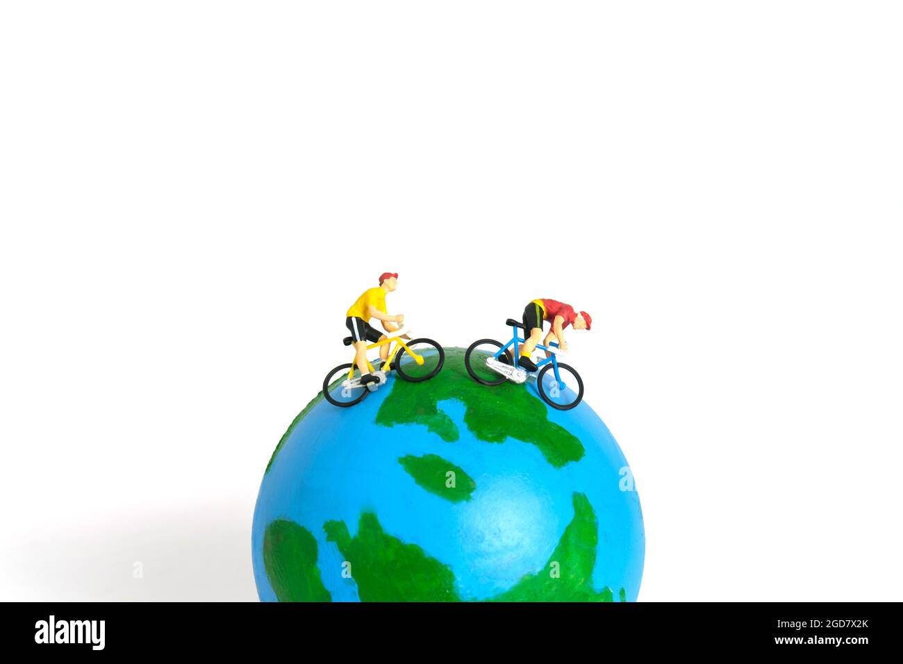 Miniatur Menschen Spielzeug Figur Fotografie. Weltfahrradtag oder Weltrundfahrt Konzept. Ein Biker, der über dem Erdball radelt, isoliert auf weißem Rücken Stockfoto