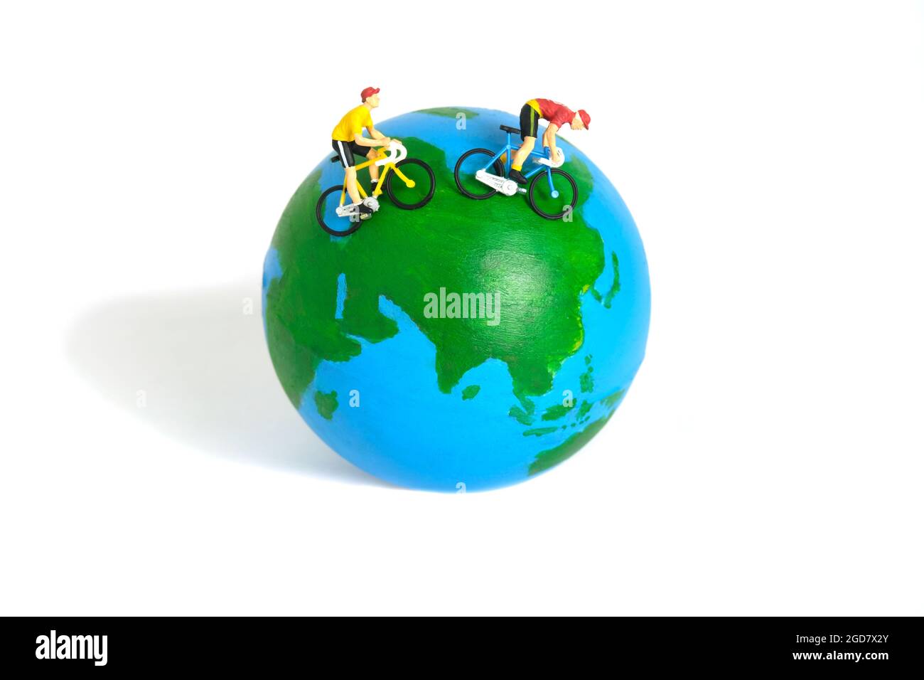 Miniatur Menschen Spielzeug Figur Fotografie. Weltfahrradtag oder Weltrundfahrt Konzept. Ein Biker, der über dem Erdball radelt, isoliert auf weißem Rücken Stockfoto