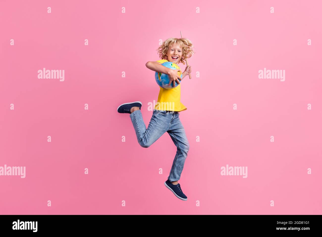 Full size Profil Seite Foto der Schule Junge glücklich positive Lächeln gehen springen halten Globus Stick isoliert über rosa Hintergrund Stockfoto