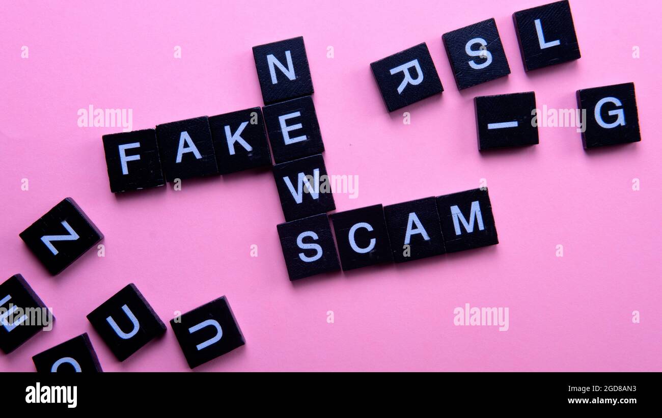 Eine Gruppe von abscheulichen Kacheln bilden Wortbetrug Fake News. Selektiver Fokus auf die Kacheln auf rosa Hintergrund isoliert Stockfoto