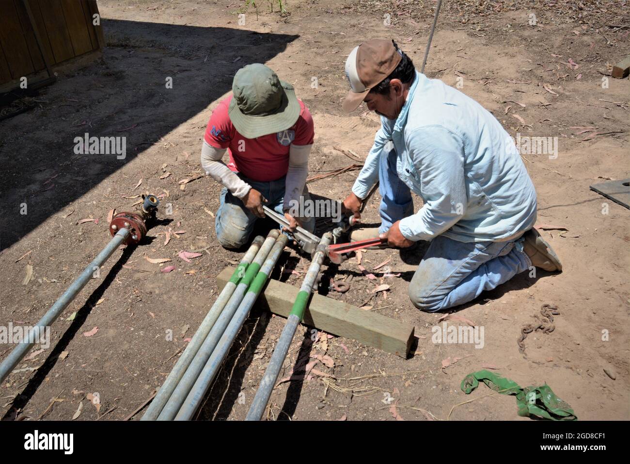 Zwei Männer, die an einer Wasserbrunnen-Pumpe zogen und die 20-Fuß-Leitung, die 26 Jahre alt war, - ethnische Hispanic, ersetzten die 180-Fuß-Arbeit an einem Tag. Stockfoto