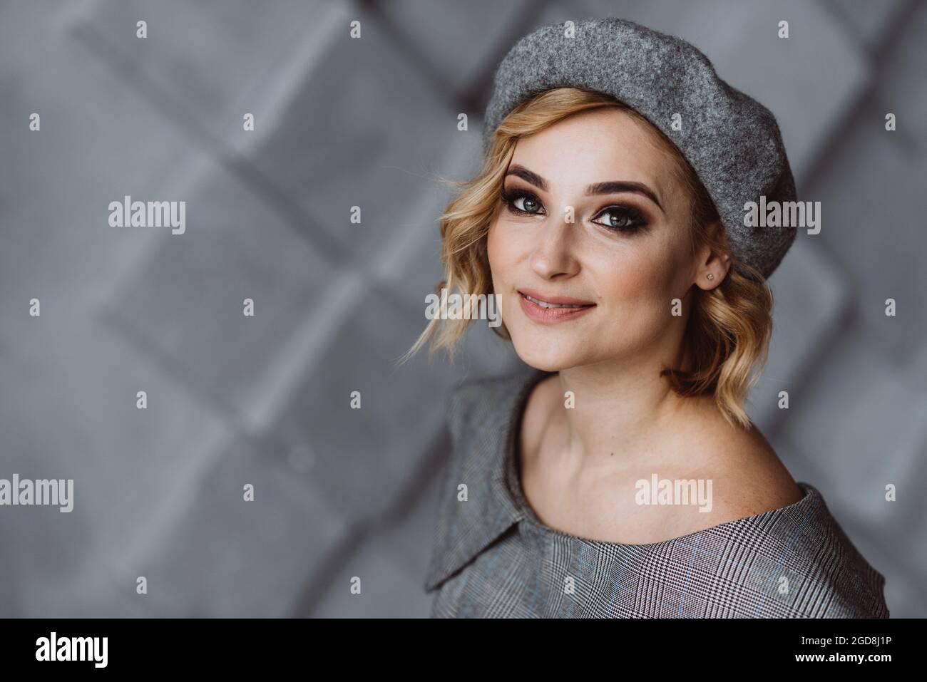 Porträt einer schönen blonden Frau mit rauchigen Augen Make-up in einer grauen Baskenmütze. Weicher, selektiver Fokus. Stockfoto