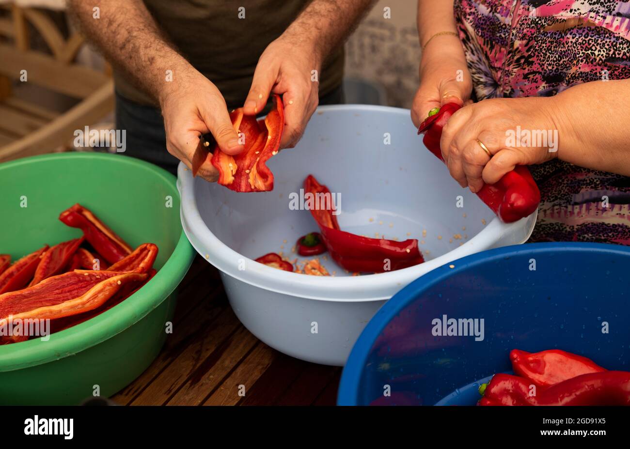Mutter und erwachsener Sohn trocknen zusammen rote Paprika, eine traditionelle spanische mediterrane Küche Stockfoto