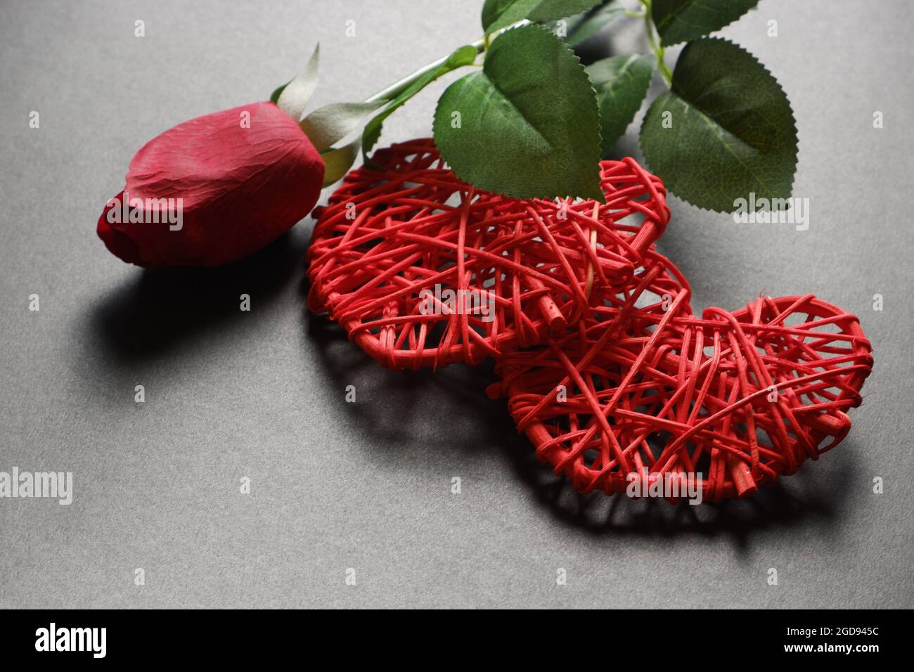 Zwei rote Herzen und eine rote Rose auf dunklem Grund. Stockfoto