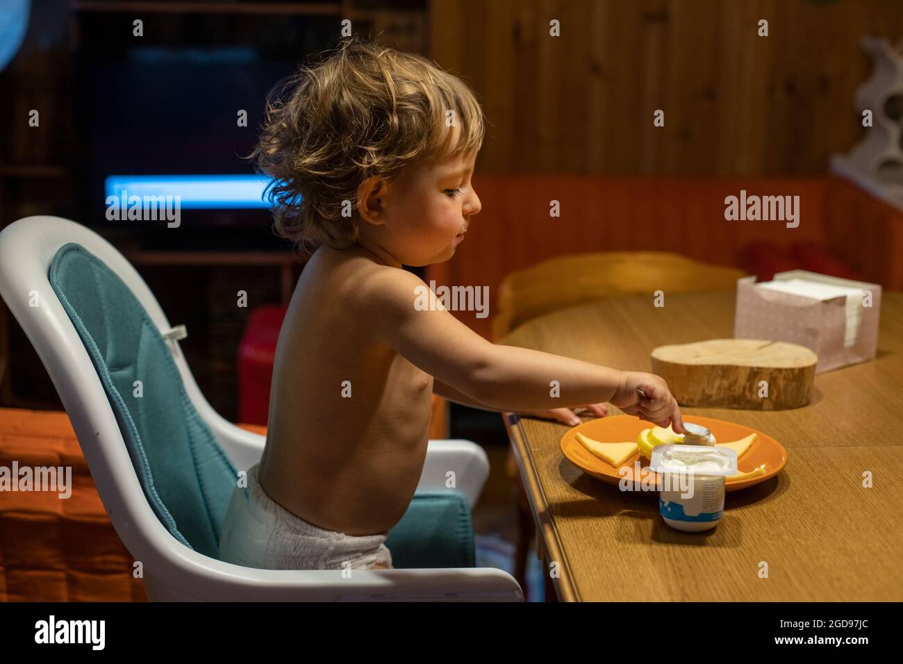 Cute kaukasischen Baby essen am Tisch. Kleinkind isst allein am Erwachsenen-Tisch Stockfoto