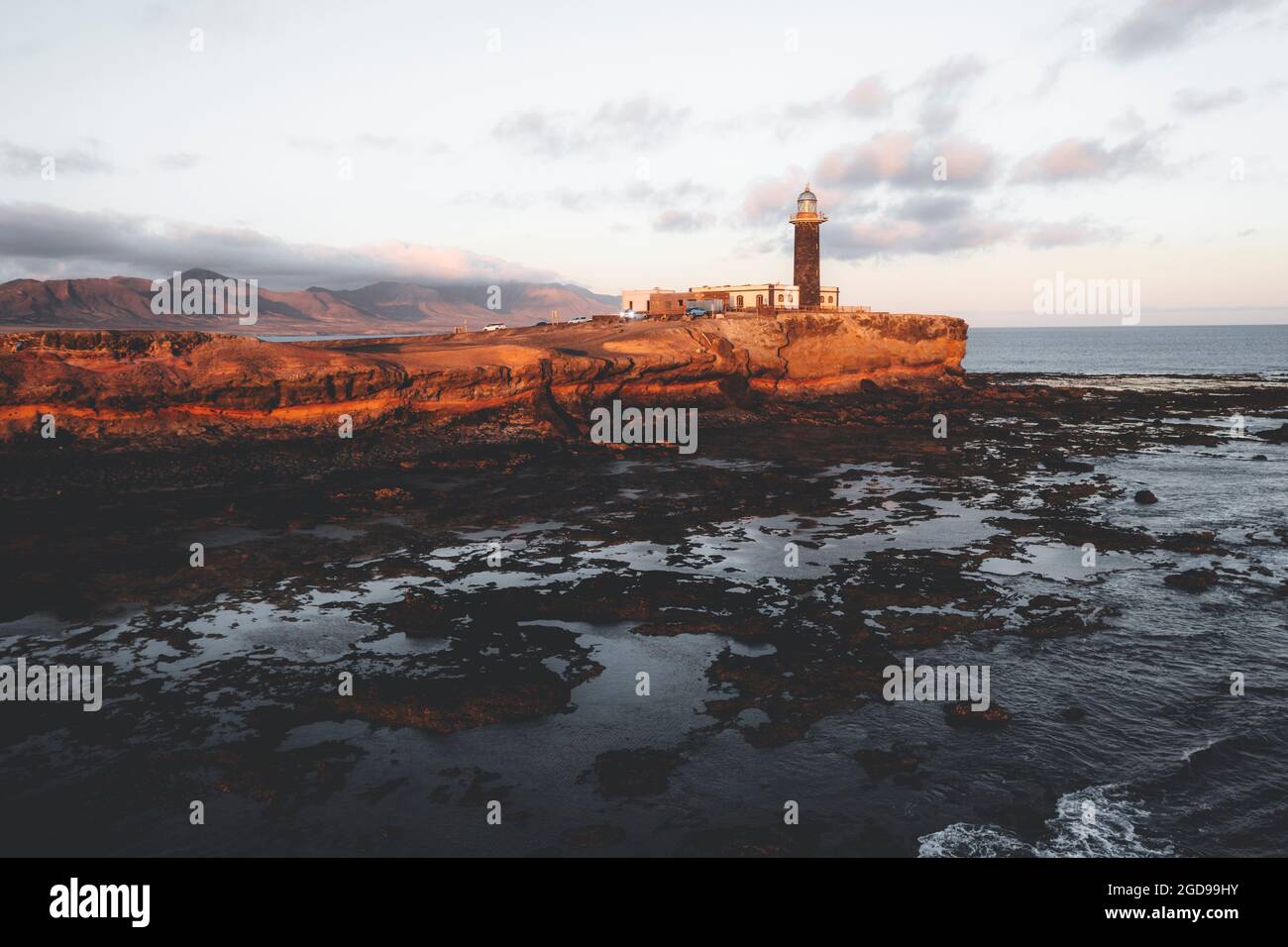 Sonnenuntergang über dem Leuchtturm von Punta Jandia (Faro de la Lola) auf vulkanischen Klippen, Fuerteventura, Kanarische Inseln, Spanien Stockfoto