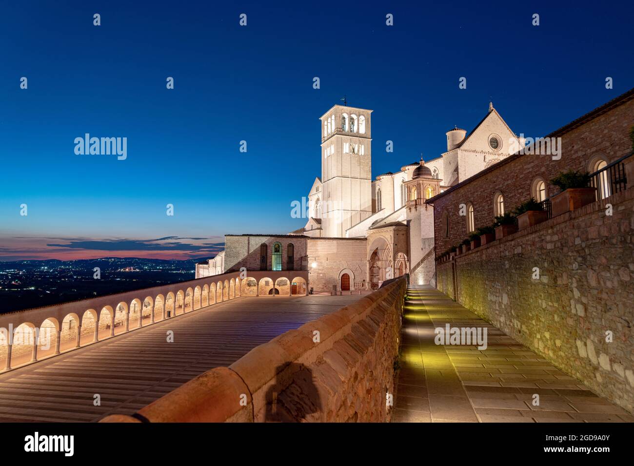 Blaue Abenddämmerung auf der Kolonnade und der beleuchteten päpstlichen Basilika des Heiligen Franziskus in Assisi, Provinz Perugia, Umbrien, Italien Stockfoto