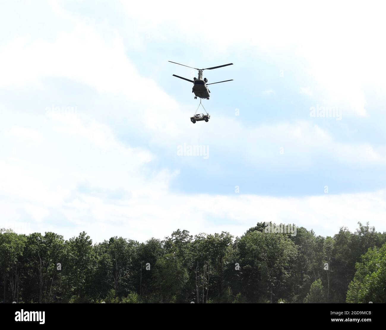 Ein CH-47 Chinook Hubschrauber hebt sich über die Bäume, nachdem Soldaten des 1. Bataillons, des 109. Infanterie-Regiments, des 2. Infanterie-Brigade-Kampfteams am 4. August 2021 in Fort Indiantown Gap, Pennsylvania, ein High Mobility Mehrzweck-Fahrzeug mit Rollen angehängt hatten. Die Schlingentraining ermöglichte es den Soldaten des Bataillons, sich mit den Fähigkeiten vertraut zu machen, die sie in der Air Assault and Pathfinder School (USA) erlernen würden Armeefoto von Sgt. Klasse Matthew Keeler) Stockfoto