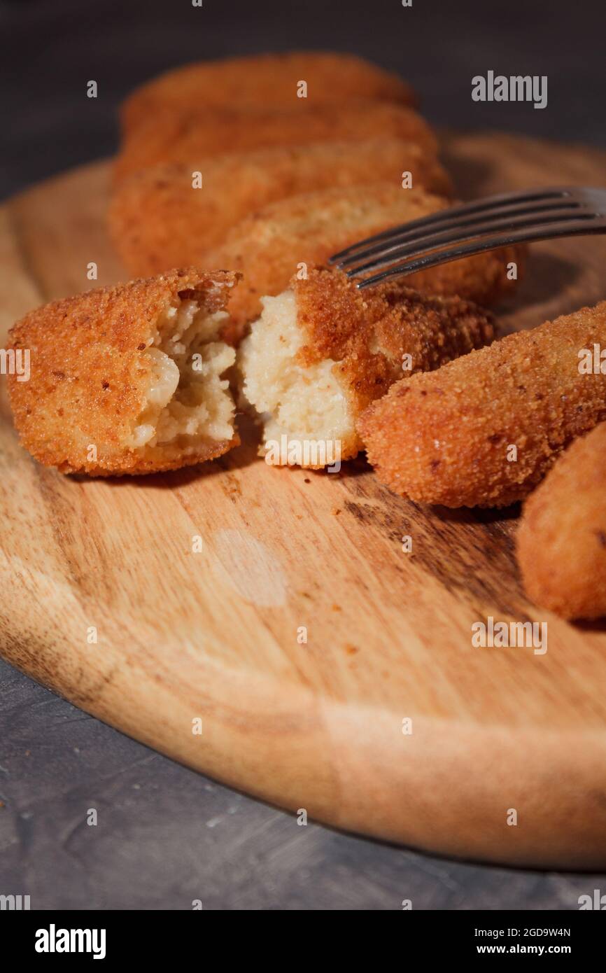 Hausgemachte traditionelle spanische Kroketten auf einem Holzbrett und schwarzem Hintergrund. Tapas. Dunkles Essen. Stockfoto