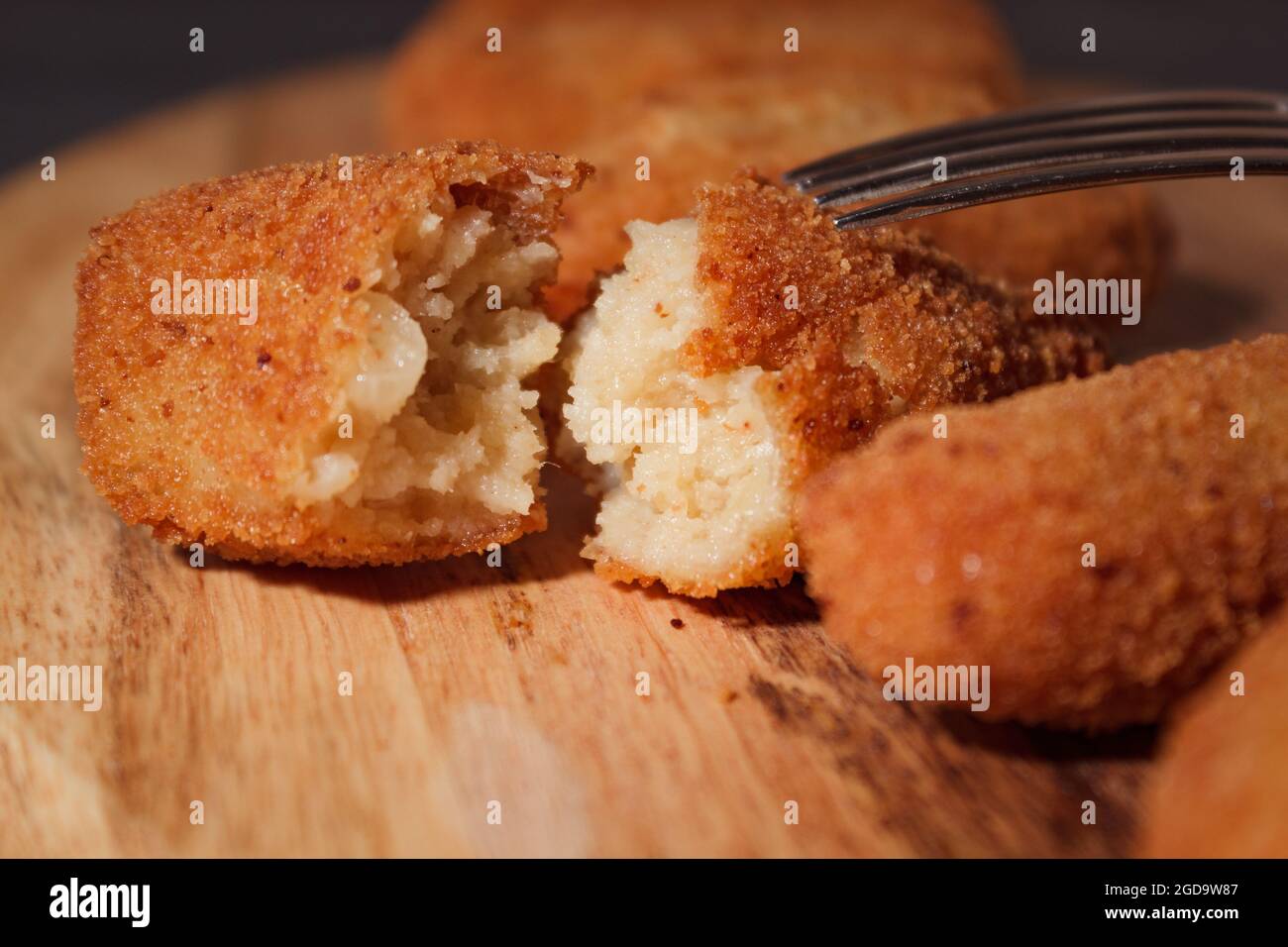 Hausgemachte traditionelle spanische Kroketten auf einem Holzbrett und schwarzem Hintergrund. Tapas. Dunkles Essen. Stockfoto