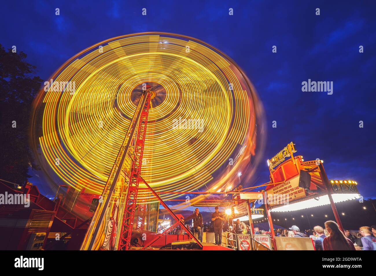 Ein großes Rad dreht sich in der Dämmerung; verschwommene Bewegung aufgrund langer Belichtung. Camp Beestival, Lulworth, Dorset, Großbritannien. Stockfoto