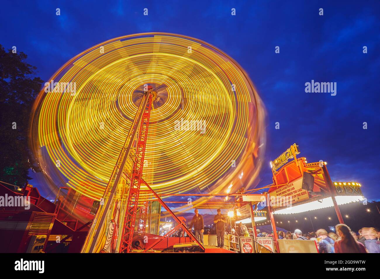 Ein großes Rad dreht sich in der Dämmerung; verschwommene Bewegung aufgrund langer Belichtung. Camp Beestival, Lulworth, Dorset, Großbritannien. Stockfoto