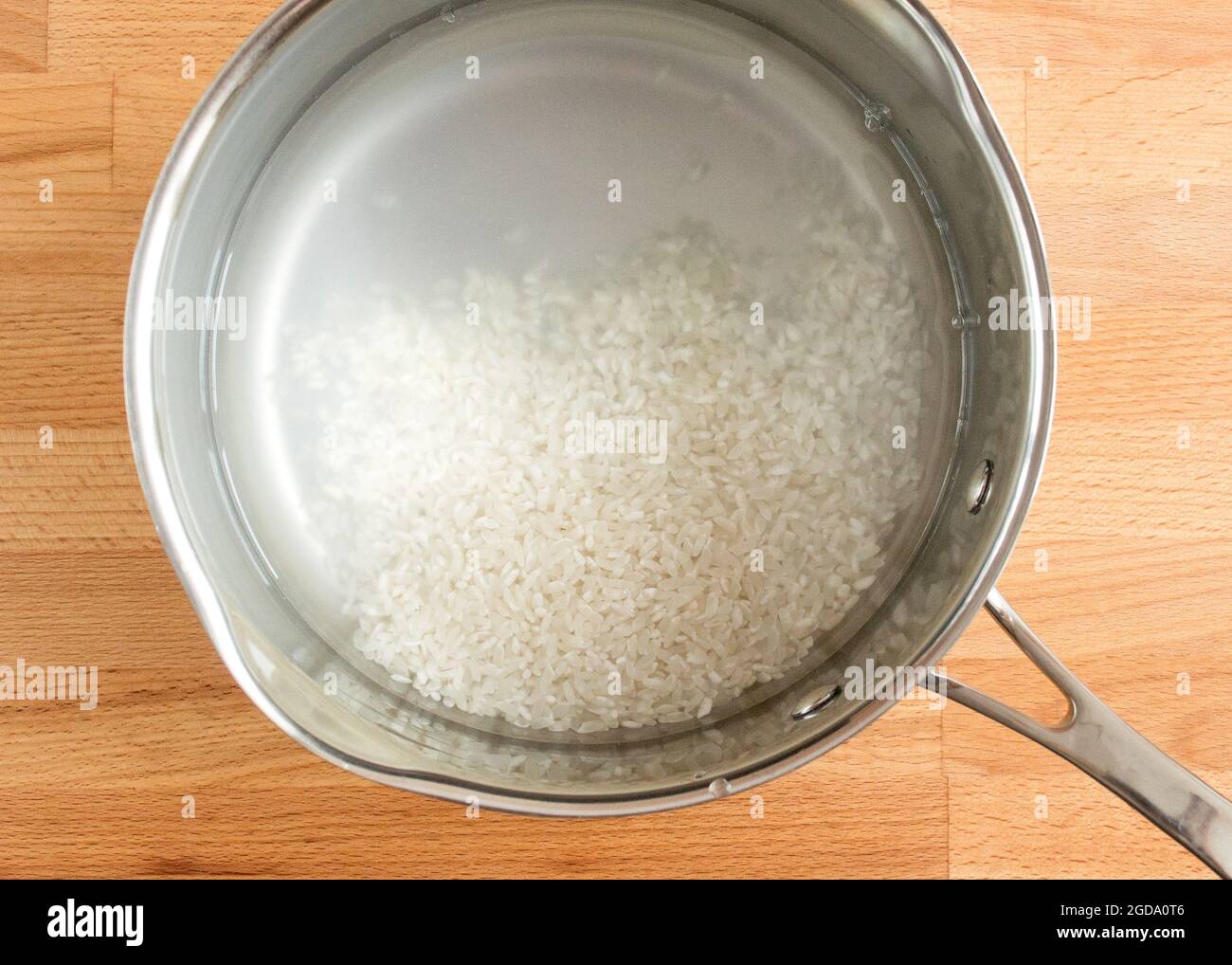 Der gewaschene Reis liegt in einer Schüssel mit Wasser. Stockfoto